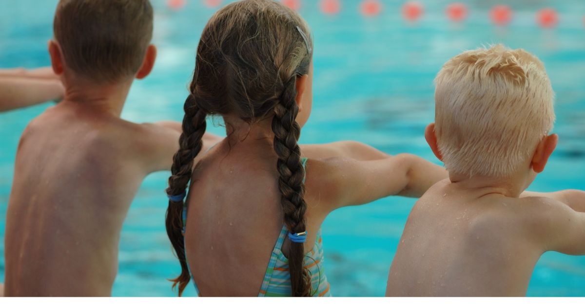 Kinderen die klaarzitten op de zwembadrand met hun armen gestrekt vooruit om in het water te duiken
