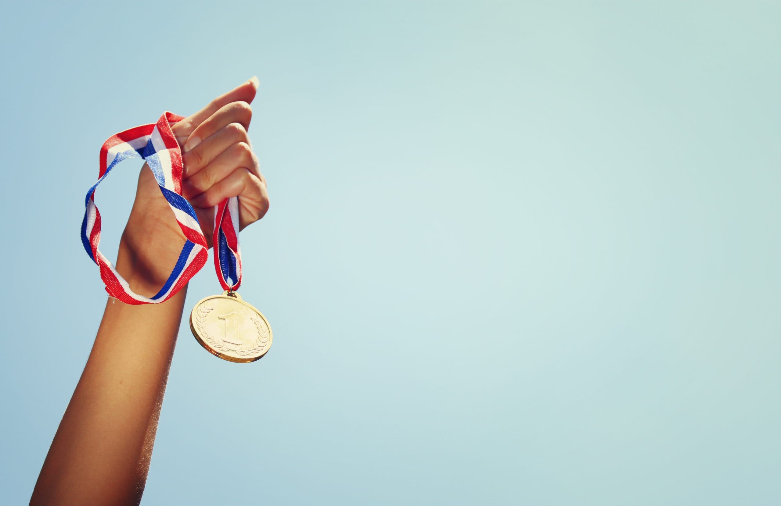Hand houdt medaille waar Nummer 1 op staat in de lucht