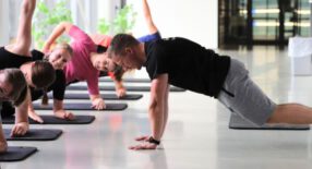 Groep doet een fitnessoefening liggend op een mat waarbij ze op 1 arm leunen en een arm in de lucht steken