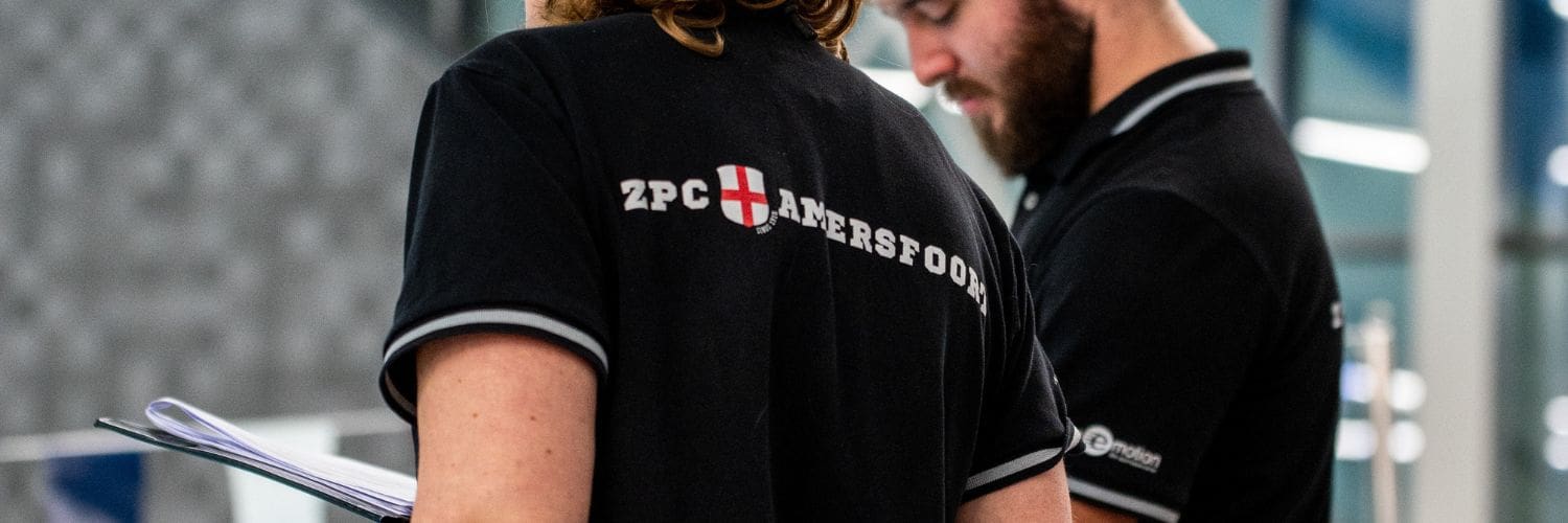 Foto van een trainer die een shirt draagt met op de rug het logo van ZPC Amersfoort