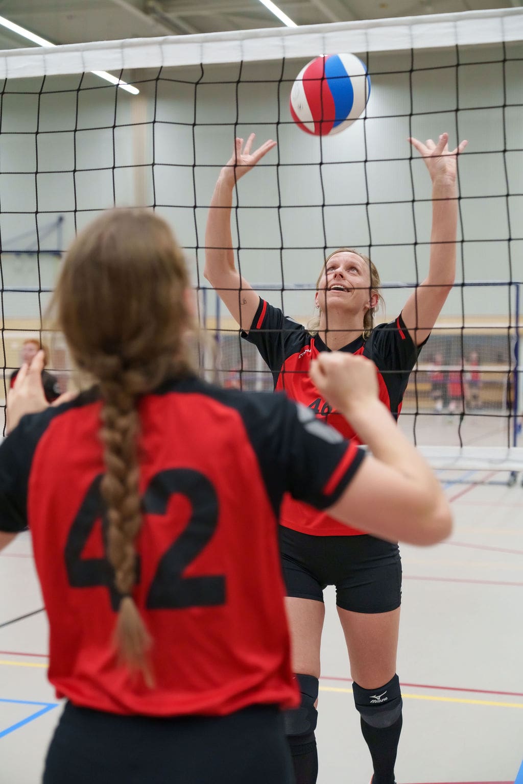 2 volleybalsters van Volleybalvereniging Wilhelmina spelen de bal over het net