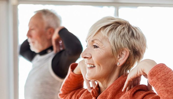 man en vrouw doen een evenwichtsoefening met hun handen naar hun schouders