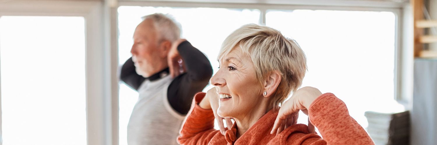 man en vrouw doen een evenwichtsoefening met hun handen naar hun schouders